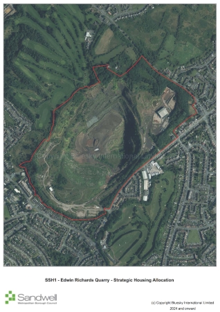 Aerial view of Edwin Richards Quarry, with its perimeter outlined in red. The quarry features open pits, built structures, and surrounding greenery, including trees and grassy areas. Residential houses and roads border the site on multiple sides.