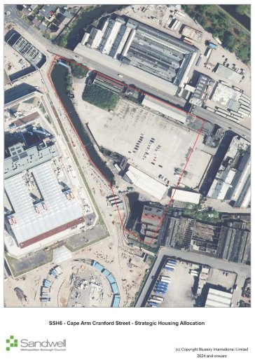 Aerial view of an urban area showing a large industrial building, surrounding roads, open space, and parking areas. A red outline marks a designated boundary for strategic housing allocation along Cape Arm Cranford Street.
